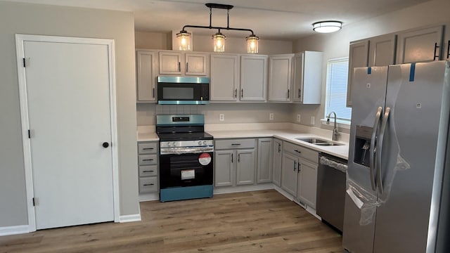 1117 Cutter Ave, Joliet, IL 60432 - kitchen with stainless steel appliances, a sink, light wood finished floors, light countertops, and hanging light fixtures
