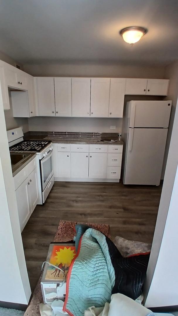 4850 S Lake Park Ave Unit 1409, Chicago, IL 60615 - kitchen featuring white appliances, white cabinets, dark wood-type flooring, and dark countertops