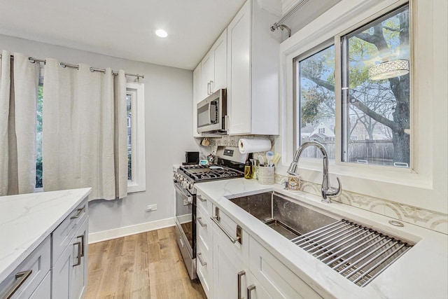 1049 Fowler Ave, Evanston, IL 60202 - kitchen with stainless steel appliances, a sink, light stone countertops, baseboards, and light wood finished floors