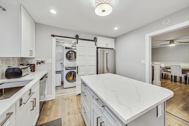 1049 Fowler Ave, Evanston, IL 60202 - kitchen featuring appliances with stainless steel finishes, stacked washer / drying machine, a barn door, light wood-style floors, and recessed lighting