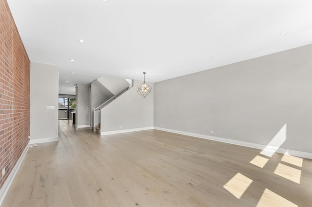 3406 N Keating Ave, Chicago, IL 60641 - unfurnished living room featuring a chandelier, light wood-type flooring, recessed lighting, and brick wall