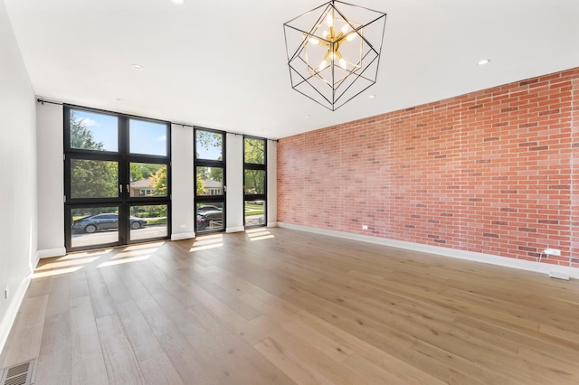 3406 N Keating Ave, Chicago, IL 60641 - empty room featuring brick wall, a chandelier, wood finished floors, floor to ceiling windows, and recessed lighting