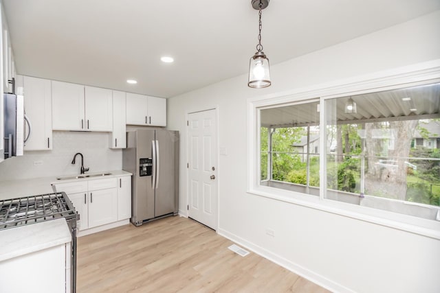 4237 Arlington Dr, Richton Park, IL 60471 - kitchen featuring appliances with stainless steel finishes, a sink, light wood finished floors, white cabinets, and decorative backsplash