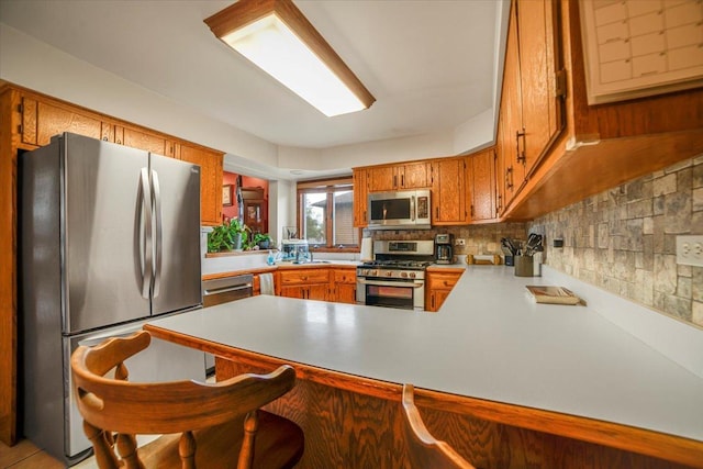 16308 S Peerless Ct, Plainfield, IL 60586 - kitchen featuring appliances with stainless steel finishes, a peninsula, light countertops, brown cabinetry, and backsplash