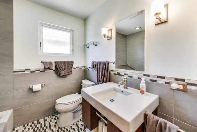5560 W Ardmore Ave, Chicago, IL 60646 - bathroom with tile walls, toilet, vanity, a tub to relax in, and tile patterned flooring