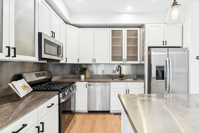 921 N Honore St Unit B, Chicago, IL 60622 - kitchen featuring appliances with stainless steel finishes, a sink, white cabinets, light wood-type flooring, and glass insert cabinets