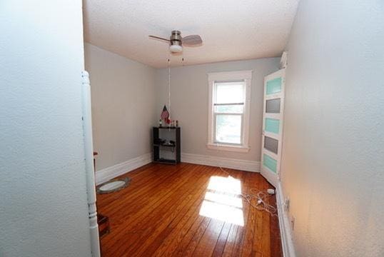 1711 S 4th St, Rockford, IL 61104 - unfurnished room with wood finished floors, a ceiling fan, baseboards, and a textured wall