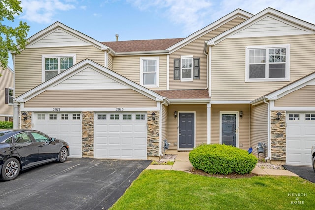 2015 Limestone Ln, Carpentersville, IL 60110 - townhome / multi-family property featuring driveway, stone siding, a shingled roof, and a front lawn