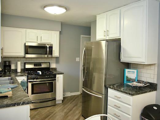 1216 Townley Dr, Bloomington, IL 61704 - kitchen with stainless steel appliances, white cabinets, tasteful backsplash, and wood finished floors