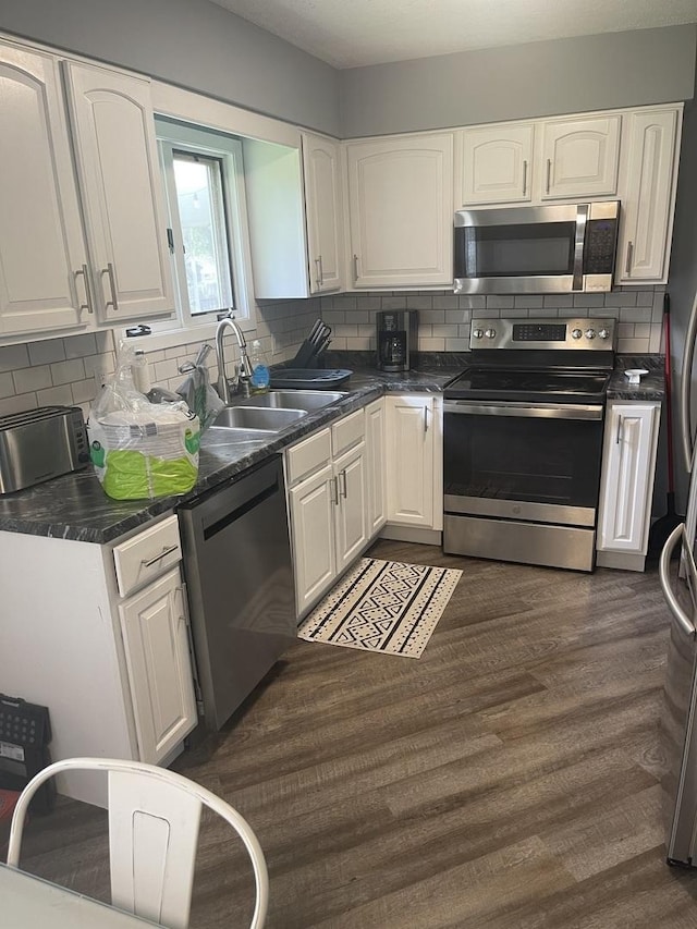 1216 Townley Dr, Bloomington, IL 61704 - kitchen featuring appliances with stainless steel finishes, white cabinetry, dark countertops, and decorative backsplash