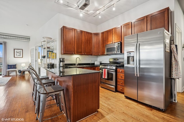 4020 N Damen Ave Unit 408, Chicago, IL 60618 - kitchen featuring appliances with stainless steel finishes, a sink, a breakfast bar, and light wood-style flooring