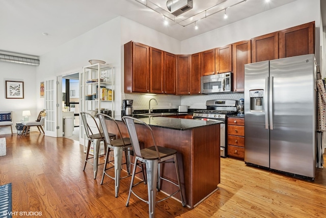 4020 N Damen Ave Unit 408, Chicago, IL 60618 - kitchen with appliances with stainless steel finishes, light wood finished floors, a breakfast bar, tasteful backsplash, and a peninsula