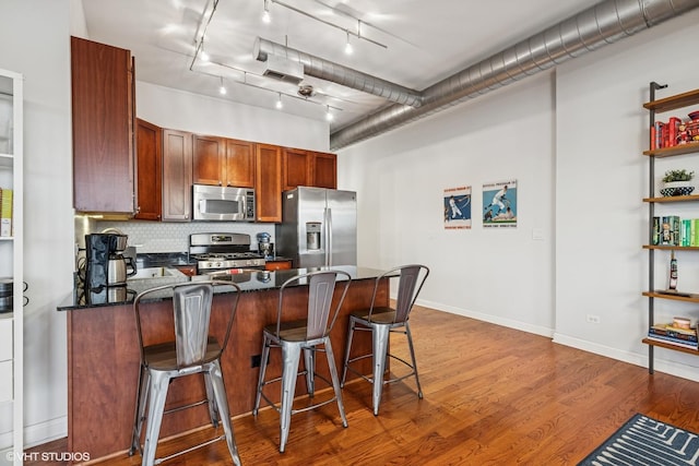 4020 N Damen Ave Unit 408, Chicago, IL 60618 - kitchen with appliances with stainless steel finishes, a peninsula, wood finished floors, a kitchen breakfast bar, and backsplash