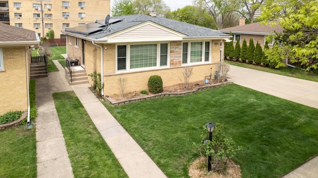 9330 Kolmar Ave, Skokie, IL 60076 - view of front facade with brick siding, solar panels, a front lawn, and roof with shingles