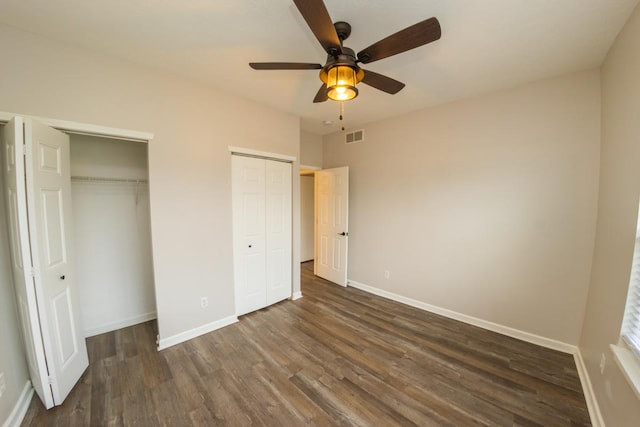 2433 River Oaks Ln Unit 6, Rockford, IL 61102 - unfurnished bedroom featuring multiple closets, dark wood-type flooring, baseboards, and a ceiling fan