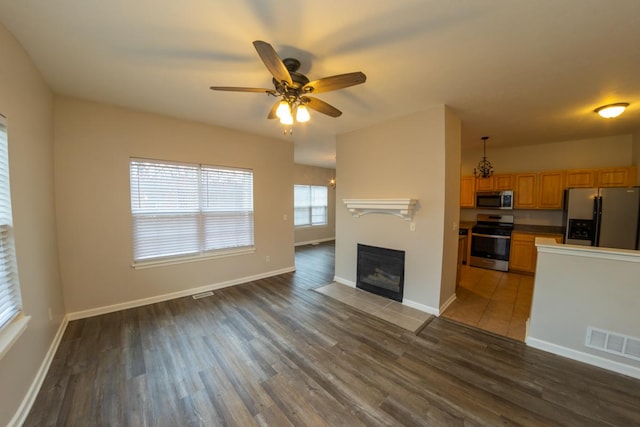 2433 River Oaks Ln Unit 6, Rockford, IL 61102 - unfurnished living room featuring wood finished floors, a fireplace with flush hearth, a ceiling fan, and baseboards