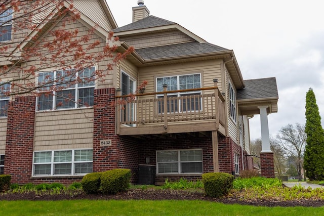 2433 River Oaks Ln Unit 6, Rockford, IL 61102 - rear view of house with brick siding, a shingled roof, a chimney, and a balcony