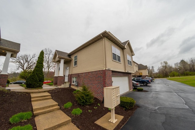 2433 River Oaks Ln Unit 6, Rockford, IL 61102 - view of property exterior featuring brick siding, a garage, and asphalt driveway