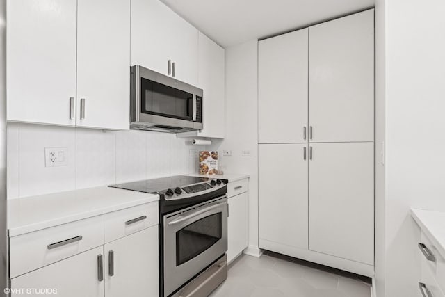 130 N Garland Ct Unit 2009, Chicago, IL 60602 - kitchen featuring stainless steel appliances, light countertops, white cabinetry, light tile patterned floors, and tasteful backsplash
