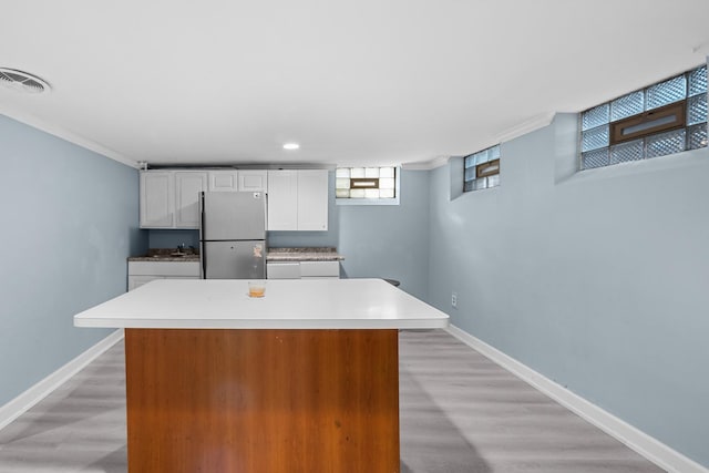 1844 N 77th Ct, Elmwood Park, IL 60707 - kitchen with freestanding refrigerator, white cabinets, ornamental molding, baseboards, and light wood-style flooring