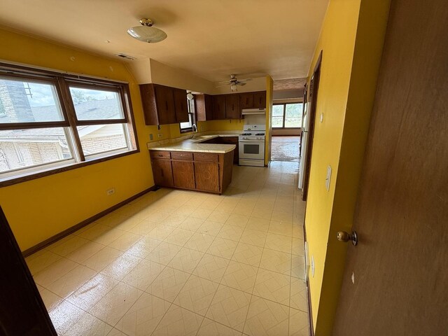 1235 S Mannheim Rd, Westchester, IL 60154 - kitchen featuring white gas stove, a peninsula, light countertops, baseboards, and ceiling fan