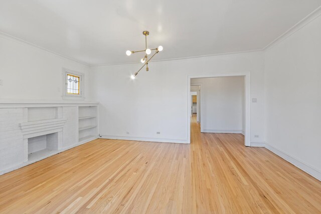 847 S Humphrey Ave Unit 3, Oak Park, IL 60304 - unfurnished living room featuring a chandelier, ornamental molding, wood finished floors, baseboards, and a brick fireplace