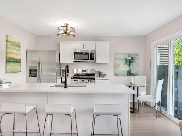 729 Bolton Way, Hanover Park, IL 60133 - kitchen with appliances with stainless steel finishes, a kitchen bar, a sink, light wood-style flooring, and light countertops