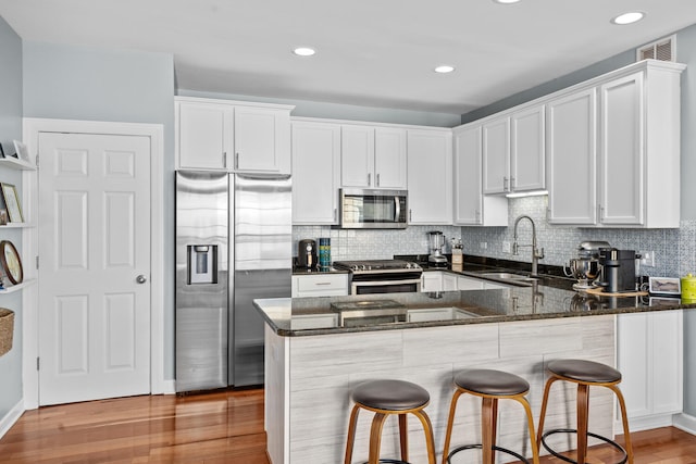 2207 N Western Ave Unit 2C, Chicago, IL 60647 - kitchen with appliances with stainless steel finishes, a sink, dark stone countertops, a peninsula, and light wood-style floors