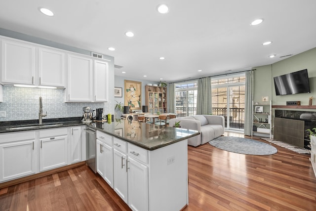 2207 N Western Ave Unit 2C, Chicago, IL 60647 - kitchen featuring a sink, open floor plan, a peninsula, wood finished floors, and white cabinetry
