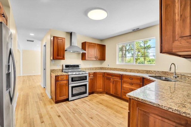 2425 W Riverside Dr, Mchenry, IL 60050 - kitchen with wall chimney range hood, stainless steel appliances, a sink, light stone countertops, and light wood-style floors
