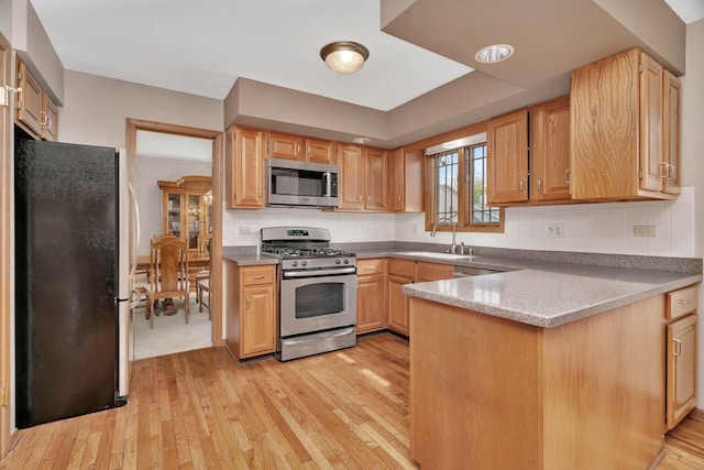 910 N Dovington Dr, Hoffman Estates, IL 60169 - kitchen with stainless steel appliances, a sink, light wood finished floors, a peninsula, and backsplash