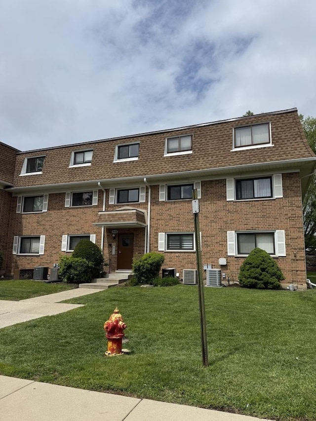 4100 Cove Ln Unit F, Glenview, IL 60025 - view of front facade with cooling unit, a front yard, a shingled roof, and brick siding