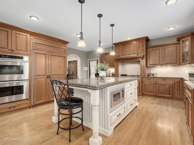 158 Los Lagos Dr, Bloomingdale, IL 60108 - kitchen featuring built in appliances, a center island, arched walkways, glass insert cabinets, and a kitchen bar