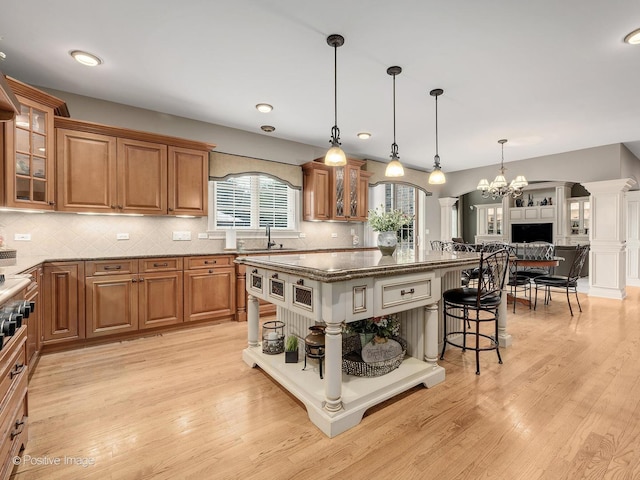 158 Los Lagos Dr, Bloomingdale, IL 60108 - kitchen with a kitchen bar, brown cabinetry, dark stone counters, a kitchen island, and light wood finished floors