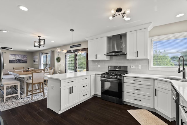 304 Turnbridge Dr, Shorewood, IL 60404 - kitchen featuring wall chimney range hood, black gas range oven, a chandelier, a sink, and a peninsula
