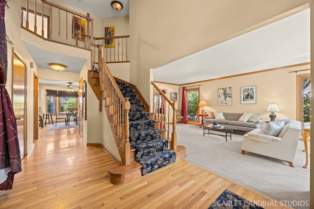 26W568 Lindsey Ave, Winfield, IL 60190 - living room featuring stairs, light wood-style floors, a towering ceiling, ceiling fan, and baseboards