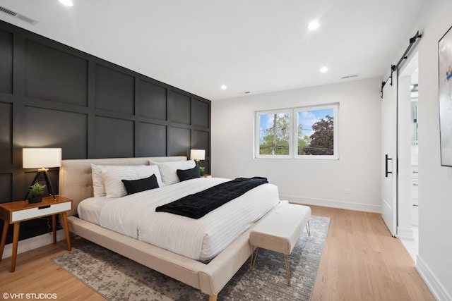 6947 N Overhill Ave, Chicago, IL 60631 - bedroom with a barn door, recessed lighting, light wood-style flooring, and baseboards