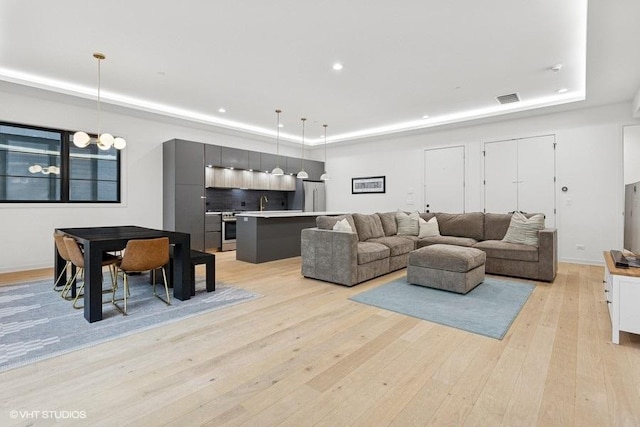 2633 N Emmett St Unit 1F, Chicago, IL 60647 - living room featuring a tray ceiling, light wood-style flooring, recessed lighting, and baseboards