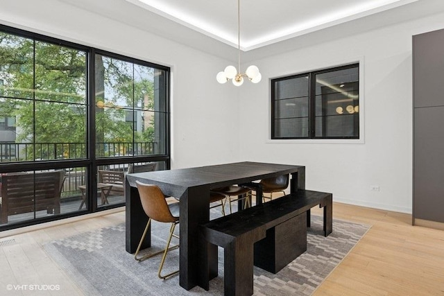 2633 N Emmett St Unit 1F, Chicago, IL 60647 - dining room featuring wood finished floors, a tray ceiling, baseboards, and a chandelier