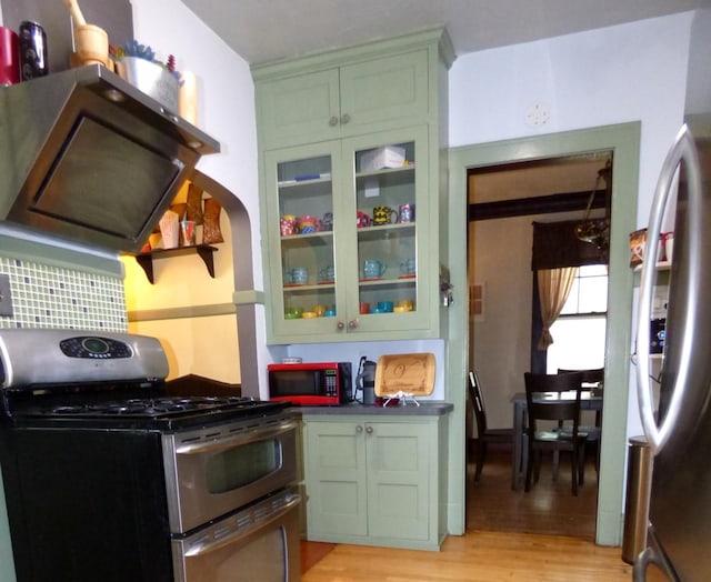 21 Woodland Ave, Elgin, IL 60123 - kitchen featuring stainless steel appliances, green cabinetry, light wood-type flooring, glass insert cabinets, and dark countertops