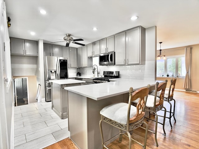9113 Elm Cir, Hickory Hills, IL 60457 - kitchen with stainless steel appliances, gray cabinets, light wood-style floors, tasteful backsplash, and light countertops