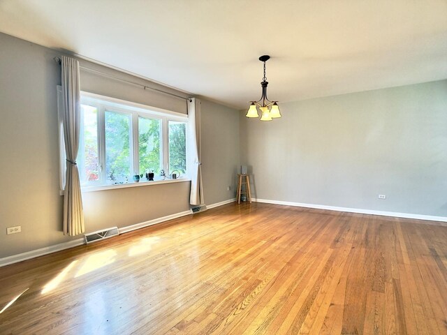 9113 Elm Cir, Hickory Hills, IL 60457 - empty room featuring wood finished floors, a chandelier, and baseboards