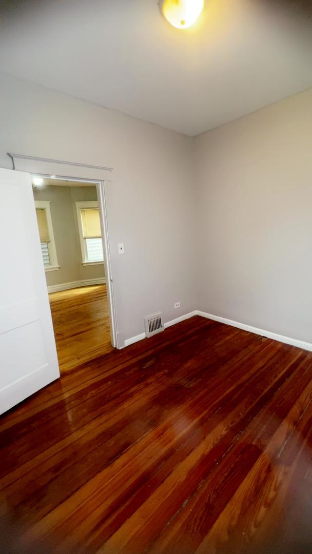 10643 S Calhoun Ave, Chicago, IL 60617 - empty room with hardwood / wood-style floors and baseboards