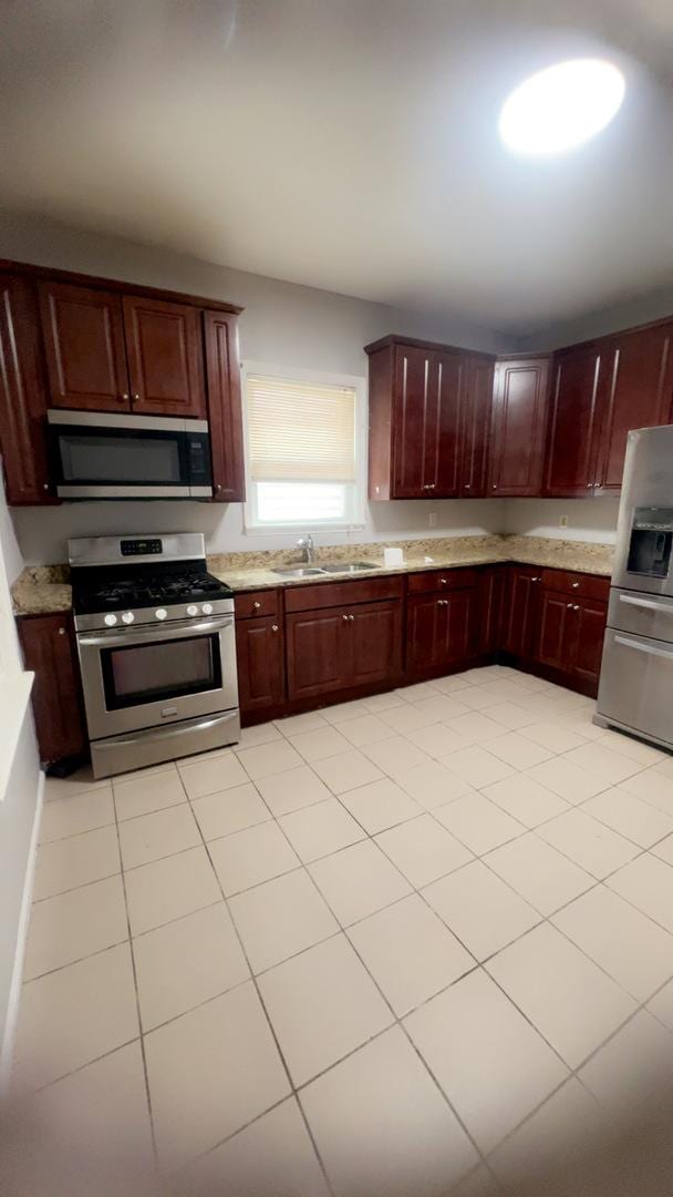 10643 S Calhoun Ave, Chicago, IL 60617 - kitchen with stainless steel appliances, a sink, reddish brown cabinets, and light tile patterned floors