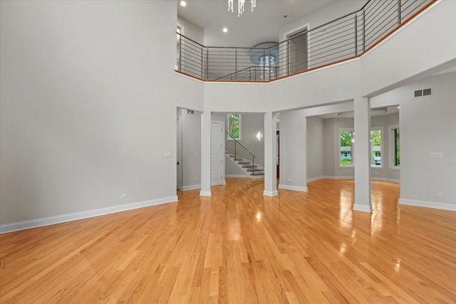 3 Crestview Ter, Buffalo Grove, IL 60089 - unfurnished living room featuring a high ceiling, stairs, light wood-style flooring, baseboards, and a chandelier