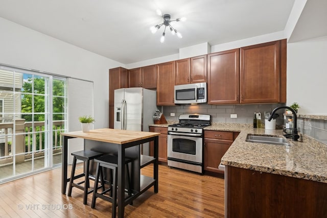 1263 Evergreen Ave, Des Plaines, IL 60016 - kitchen with stainless steel appliances, a sink, decorative backsplash, light stone countertops, and wood finished floors