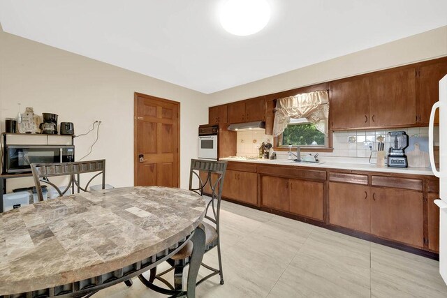 11400 S Ridgeland Ave, Worth, IL 60482 - kitchen featuring oven, light countertops, tasteful backsplash, a sink, and brown cabinets