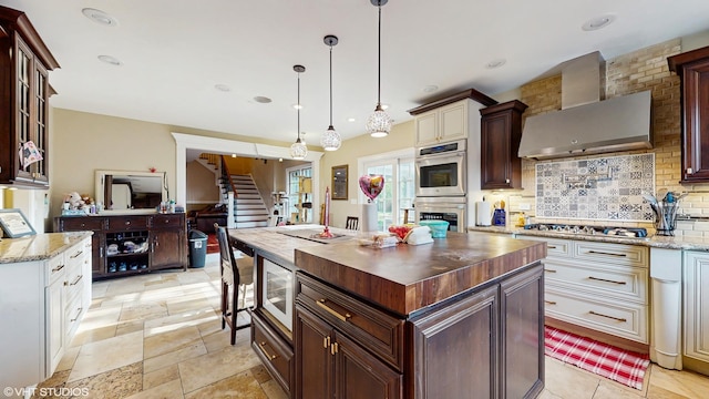8N594 S Mclean Blvd, South Elgin, IL 60177 - kitchen featuring stainless steel appliances, decorative backsplash, wall chimney exhaust hood, wood counters, and decorative light fixtures