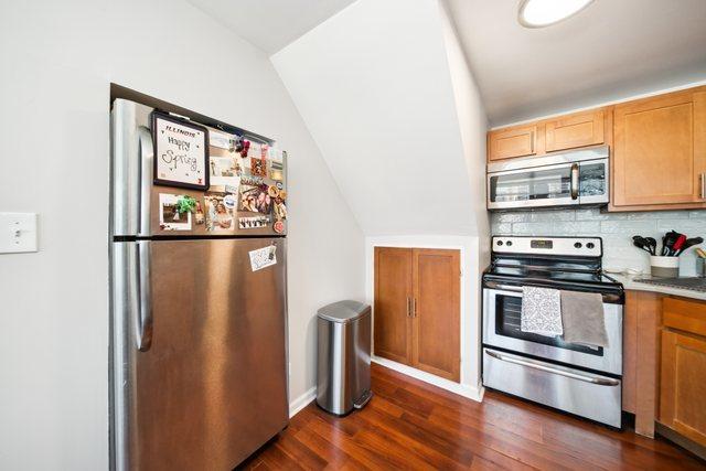 1221 N Dearborn St Unit 810S, Chicago, IL 60610 - kitchen featuring appliances with stainless steel finishes, dark wood-style flooring, decorative backsplash, and vaulted ceiling