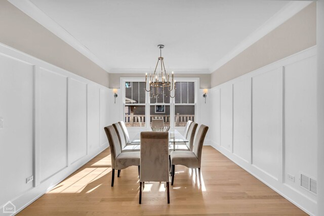 4920 Stonewall Ave, Downers Grove, IL 60515 - dining space featuring a decorative wall, a chandelier, crown molding, and light wood-style floors